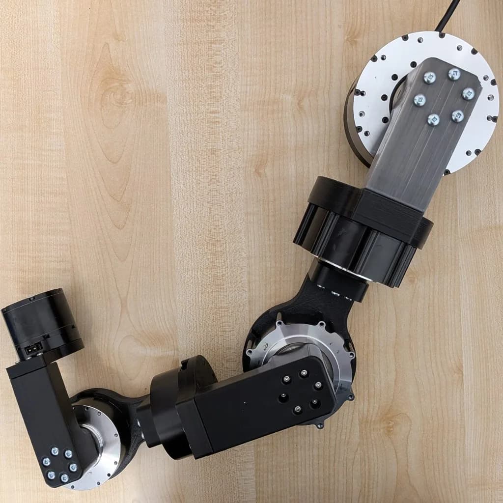 Assembled 3D-printed current-generation robot arm laid on a wooden bench