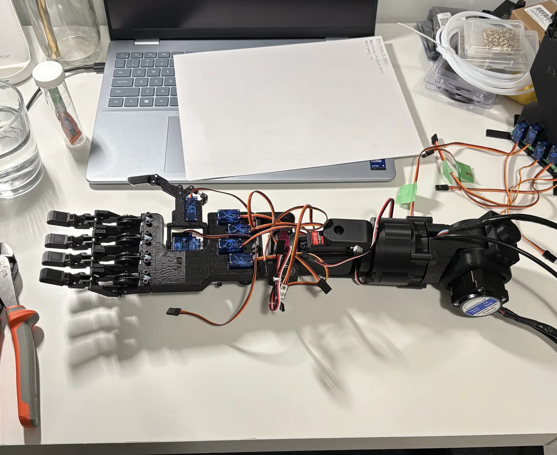 Earlier arm and hand prototype laid out on a workbench