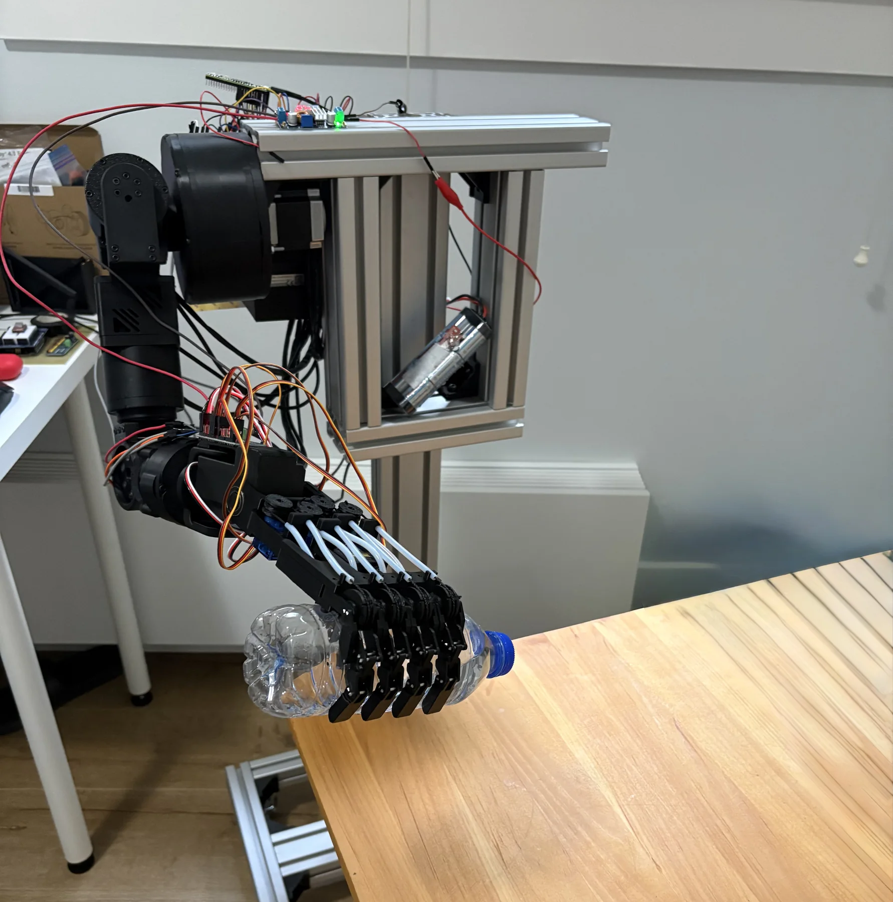 Earlier physical arm prototype grasping a plastic bottle